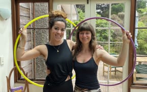 Two women holding hula hoops and smiling.