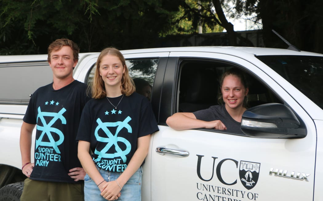 Chloe Fraser (seated in car), Tim Greene, and Isabella Fanselow. 
Members of the Christchurch Student Volunteer Army who are organising rides for members of the Muslim student community.