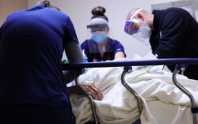 Clinicians care for a Covid-19 patient in a California hospital's isolation area