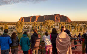 People enjoying the first sunlight of sunrise at Uluru (Ayers Rock), the sacred sandstone rock formation, Uluru-Kata Tjuta National Park, UNESCO World Heritage Site, Northern Territory, Australia,