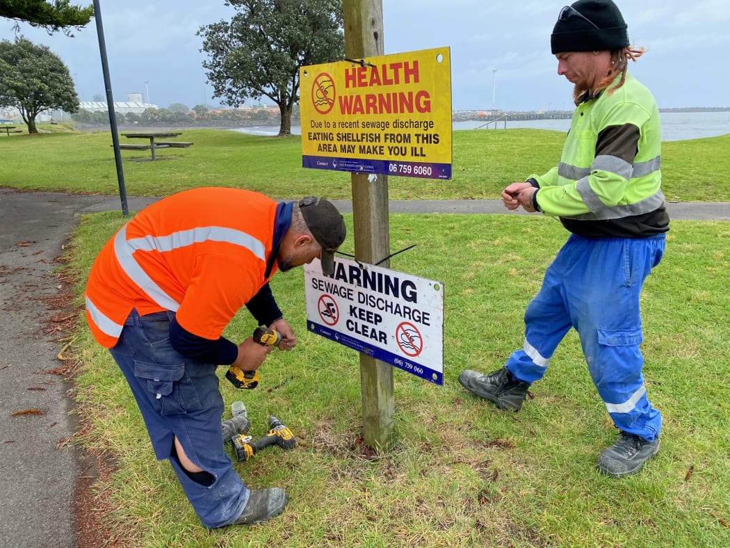 New Plymouth Council workers erect public health warning signs at Ngamotu Beach.