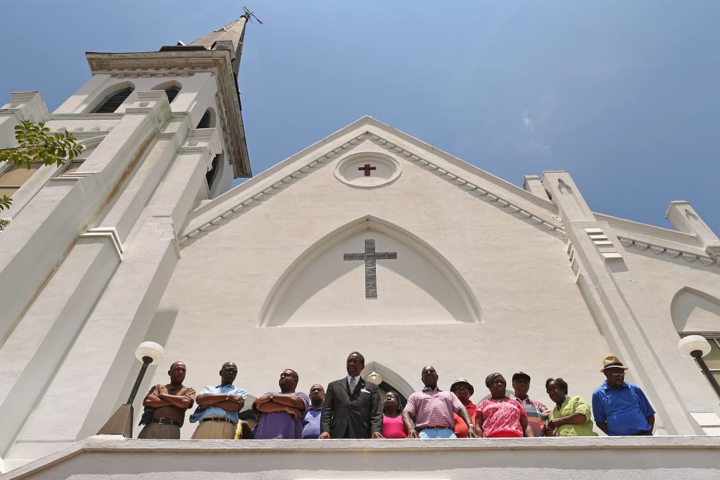 Members of the historic Emanuel African Methodist Church stand in front of the church and announce that services and Sunday school will go ahead as scheduled on Sunday.
