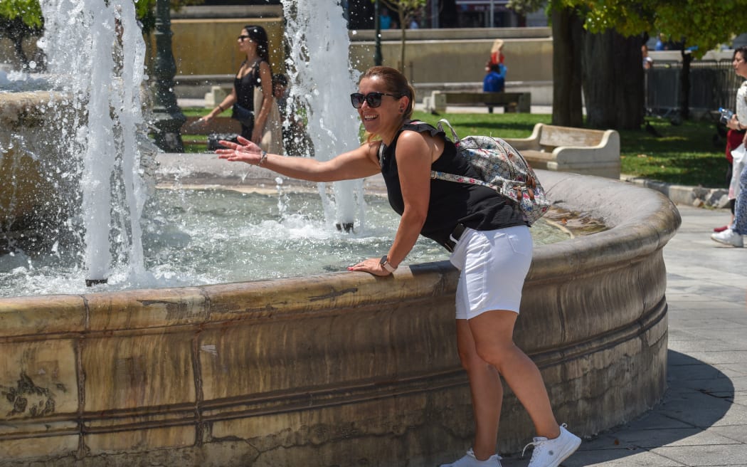 A woman tries to cool off at a fountain at Syntagma Square during heatwave 'Cleon' in Athens, Greece, on July 13, 2023.