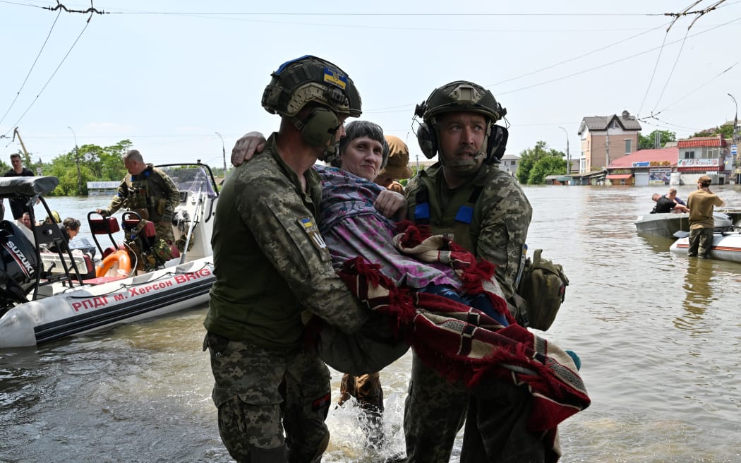Soldados ucranianos llevan a un residente discapacitado a un bote durante la evacuación de un área inundada en Kherson, el 8 de junio de 2023, luego de que la presa de Khakovka fuera destruida.