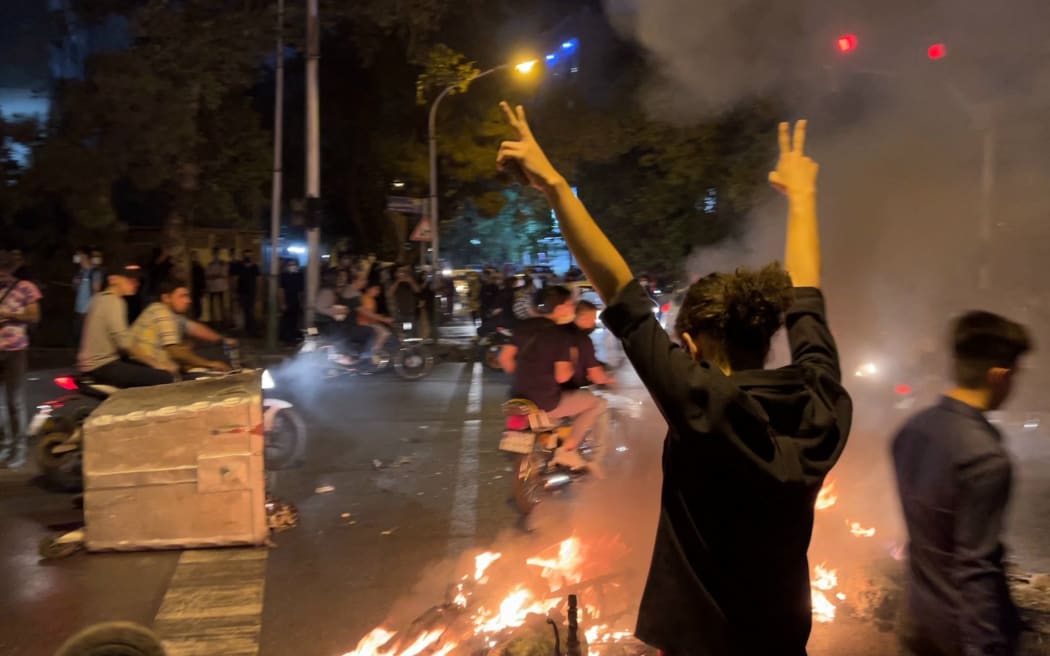 A picture obtained by AFP outside Iran shows shows a demonstrator raising his arms and makes the victory sign during a protest for Mahsa Amini, a woman who died after being arrested by the Islamic republic's "morality police", in Tehran on September 19, 2022.