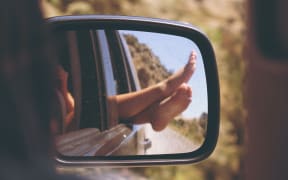 a pair of feet reflected in a car's rear view mirror