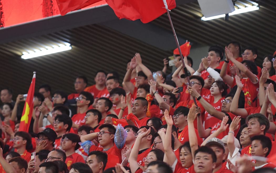 Fans wave during an international friendly football match in China, against Palestine in Dalian, in June.