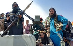 Taliban fighters sit on a vehicle on a street in Laghman province on 15 August 2021.