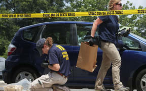 Members of the FBI Evidence Response Team collect evidence at the site of the shooting at Eugene Simpson Stadium Park.