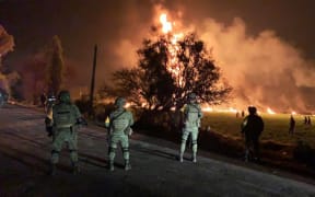 Mexican soldiers standing guard near a fire after a leaking gas pipeline triggered a blaze in Tlahuelilpan, Hidalgo state, on January 18, 2019.