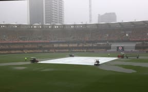 Groundmen cover the pitch area after rain stop the play on day two of the fourth cricket Test match between Australia and India at the Gabba in Brisbane on January 16, 2021.