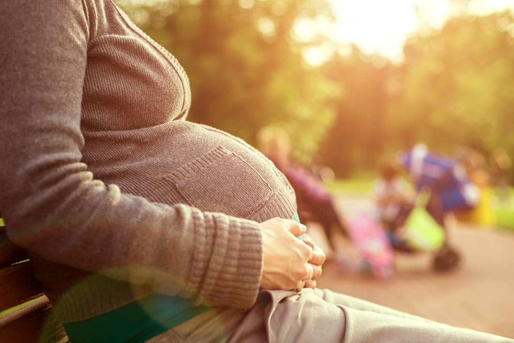 Pregnant woman sitting on a bench.