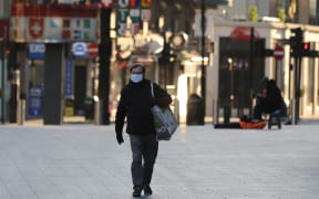 A man wears a medical mask as a precaution against coronavirus at deserted Leicester Square in London, United Kingdom on March 23, 2020.