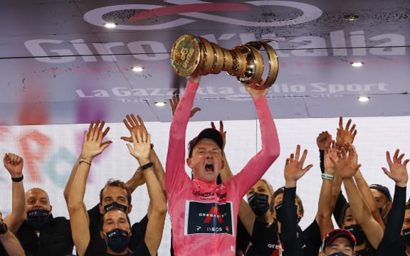 Overall race winner Team Ineos rider Great Britain's Tao Geoghegan Hart wearing the leader's pink jersey holds the "Never ending trophy" (Trofeo Senza Fine) as he celebrates on podium after the the 21st and final stage of the Giro d'Italia 2020 cycling race.