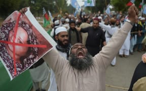A Pakistani supporter of the Ahle Sunnat Wal Jamaat (ASWJ), a hard line religious party, holds an image of Christian woman Asia Bibi during a protest rally following the Supreme Court's decision to acquit Bibi of blasphemy.