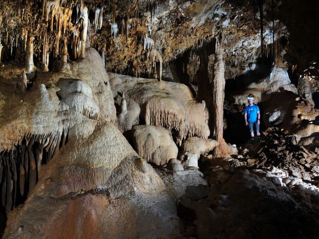 Adam Hartland in a cave filled with speleothems such as stalactites, stalagmites and flowstones, all of which hold records of past climate.