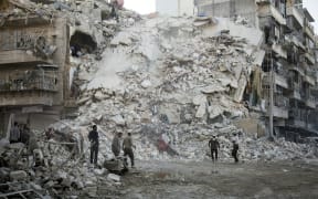 Members of the Syrian Civil Defence, known as the White Helmets, search for victims amid the rubble of a destroyed building following reported air strikes in the rebel-held Qatarji neighbourhood of the northern city of Aleppo on Monday.