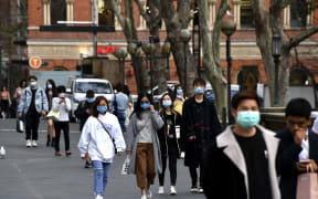 People wearing face masks walk on a street in the central business district of Sydney on August 3, 2020.