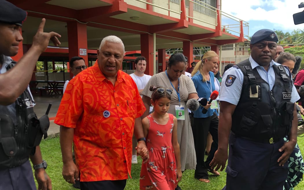 Frank Bainimarama leaves a polling station with his granddaughter