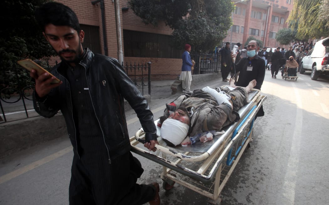 People push a stretcher carrying an injured victim after a mosque blast inside the police headquarters, at a hospital in Peshawar on January 30, 2023. - A blast at a mosque inside a police headquarters in Pakistan on January 30 killed at least 25 worshippers and wounded 120 more, officials said. (Photo by Zafar IQBAL / AFP)