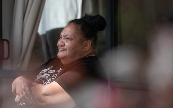 Roimata Smith sits outside of her house with her arms crossed.