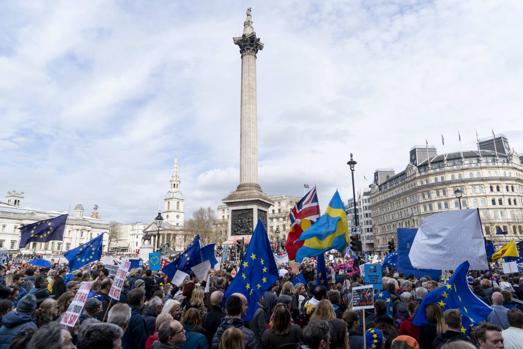 People hold up placards and European Union flags as they pass Trafalgar Square on a march and rally organised by the pro-European People's Vote campaign for a second EU referendum in central London on March 23, 2019.