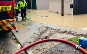 Fire fighters trying to pump water from a Plimmerton home.