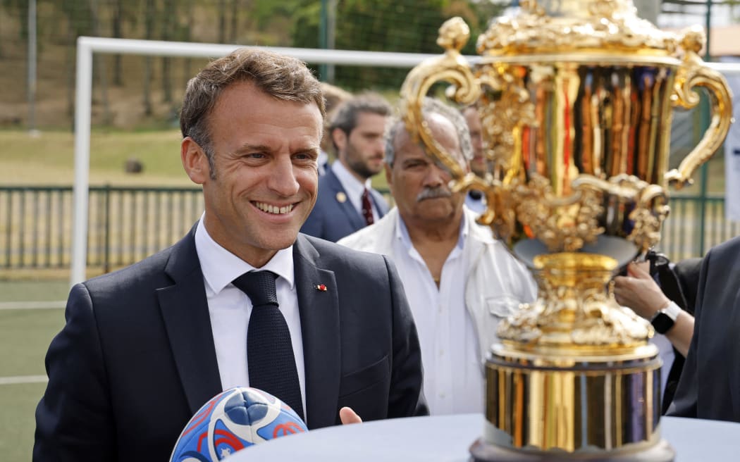 French President Emmanuel Macron looks at the Webb Ellis Cup trophy during his visit to Noumea