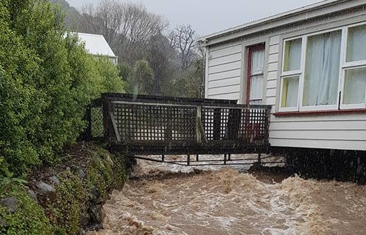 A flooded stream runs past a house in Akaroa