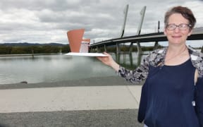 Photographer Diane Stoppard with the model of the camera obscura sculpture, in front of Whangarei's bascule bridge.