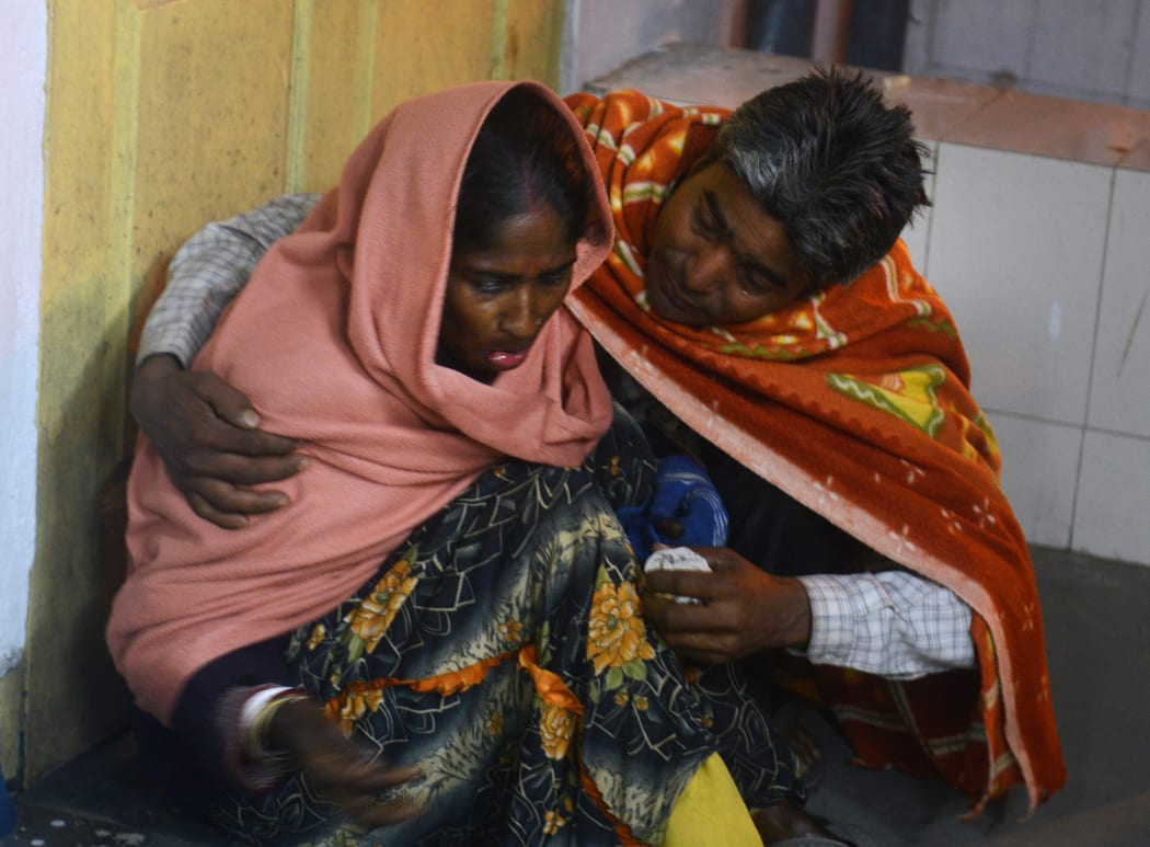 An injured Indian woman is comforted by her husband as she waits for treatment