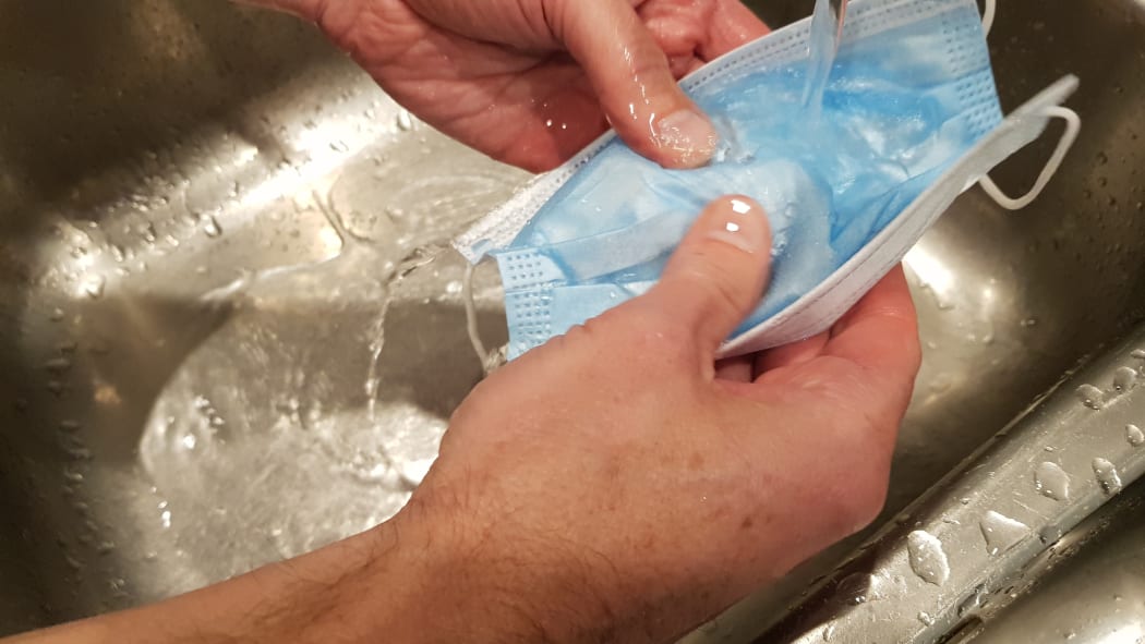 Microbiologist Richard Everts washing a disposable mask in warm water.