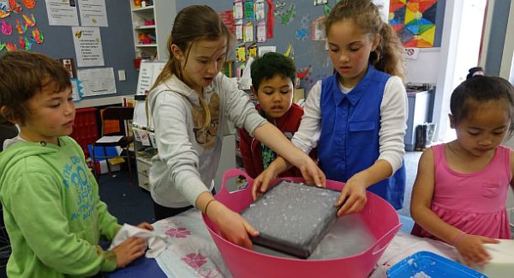 Primary school children at Hampton Hill School in Tawa gathered around table scooping out slush on a screen to make paper