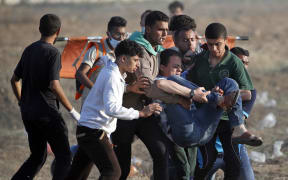Palestinians carry away an injured protester who was shot in his leg during clashes with Israeli forces east of Gaza City.