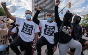 Following a night of confrontations protesters raise their fists as they knell in front of a police station in Detroit, Michigan on May 30, 2020 to protest the killing of George Floyd who died while a white officer held his knee on his neck for several minutes. -