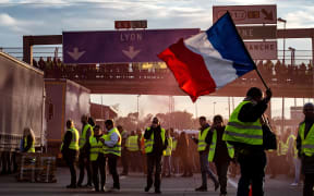A "Yellow Vest" (Gilets Jaunes in French) protester waves a French flag on the A6 motorway in Villefranche-sur-Saone on November 24, 2018.