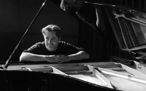 A black and white picture of Darren Pickering sitting at the piano