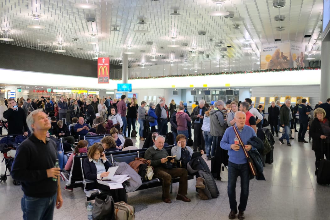 Travellers waiting at Hannover Airport after an incident.