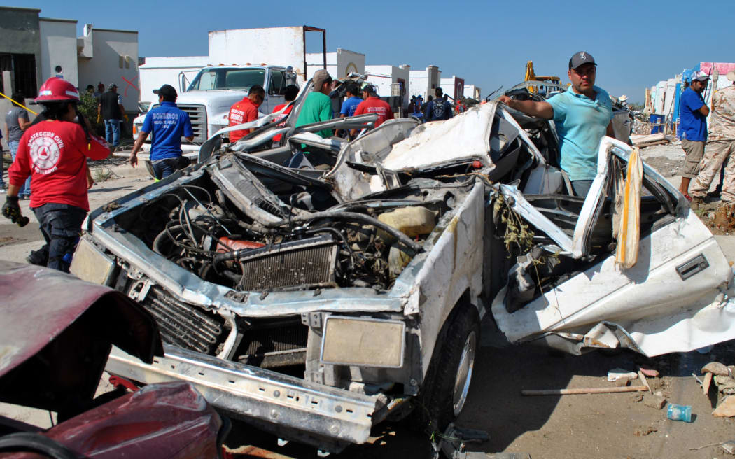 People survey a destroyed car in Ciudad Acuna, Mexico after a tornado ripped through the town.