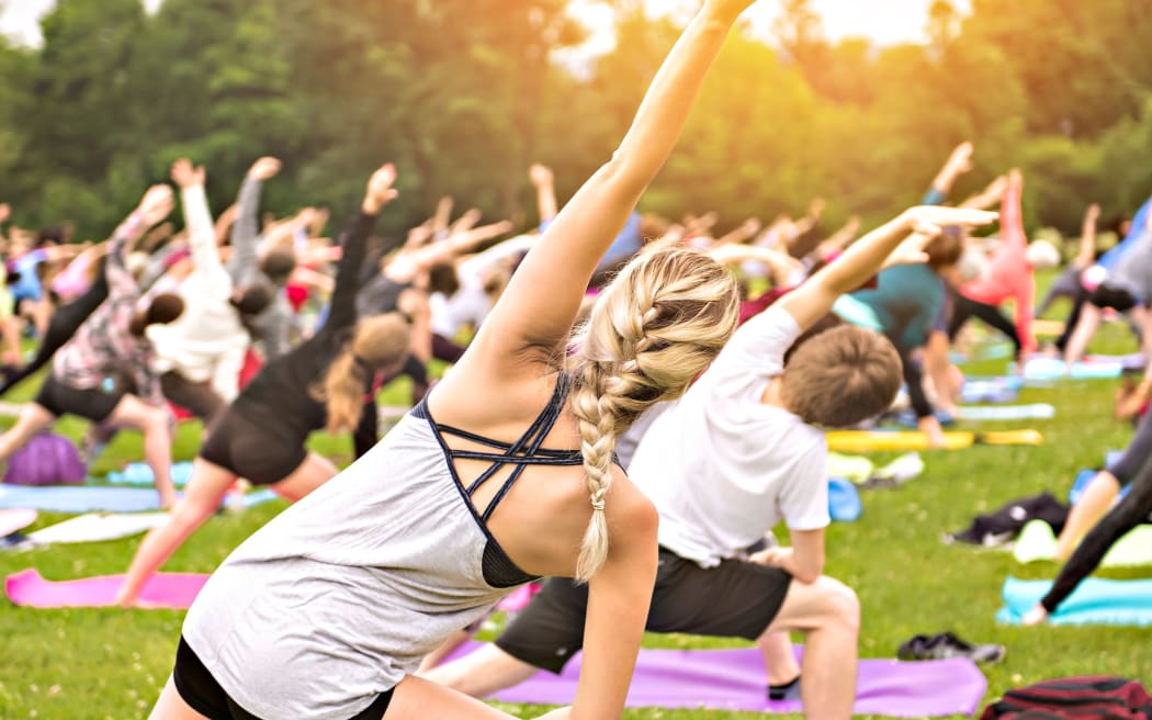 Un folto gruppo di adulti partecipa a una lezione di yoga all'aperto in un parco