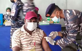 A Papuan man receives a dose of the Sinovac Covid-19 coronavirus vaccine conducted by Indonesian navy medical team at Sorong seaport, in Sorong, West Papua, July 18, 2021.
