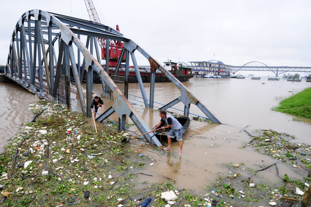 Chinese workers clear away garbage floating on the flooded Yangtze River.
