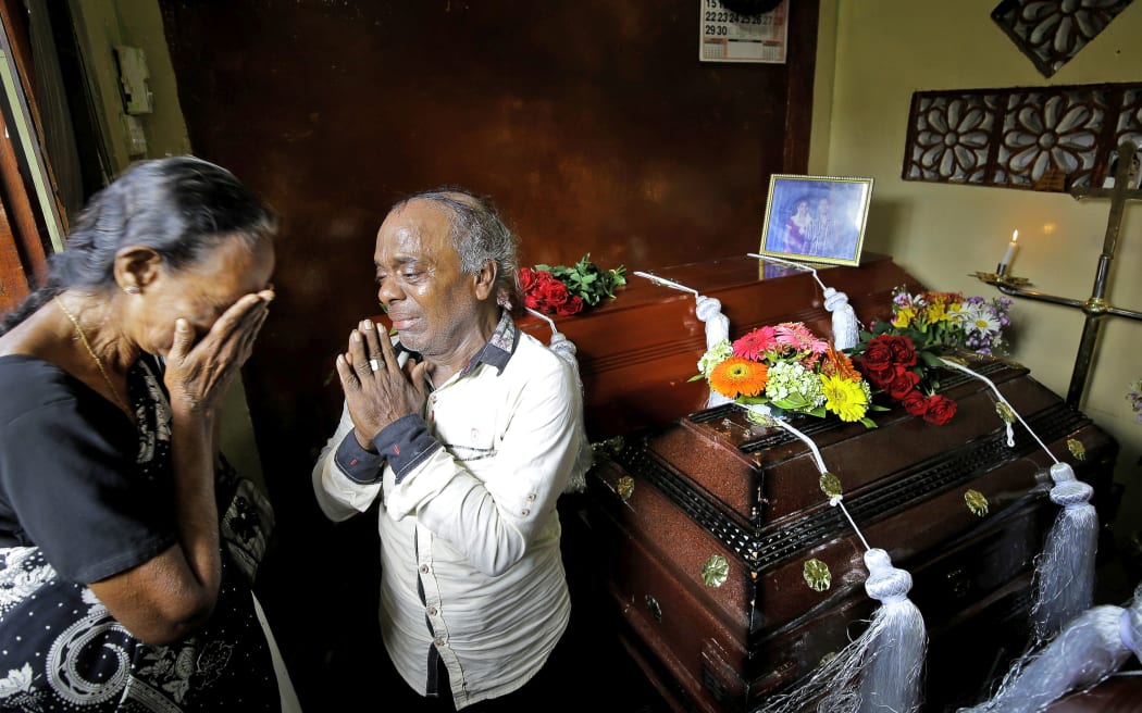 A Sri Lankan family mourns next to the coffins of their three family member, all victims of Easter Sunday bombing, in Colombo, Sri Lanka, Tuesday, April 23, 2019.