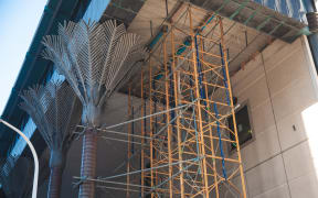 Scaffolding by the metal nikau sculptures of the Wellington Central Library building.