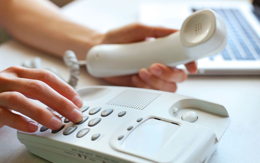 A person dials a number on a home landline phone (file)