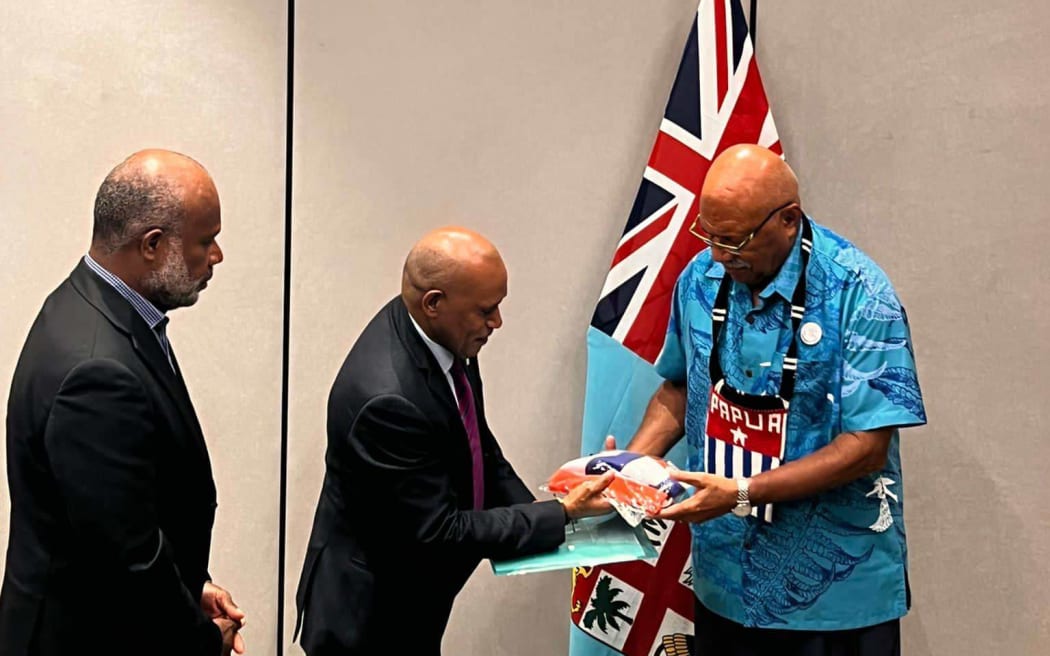 Benny Wenda, left, hands a Morning Star flag to Sitiveni Rabuka