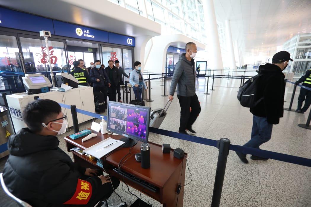 Staff members take passengers' body temperature at Tianhe International Airport in Wuhan, capital of central China's Hubei Province, Jan. 21, 2020.