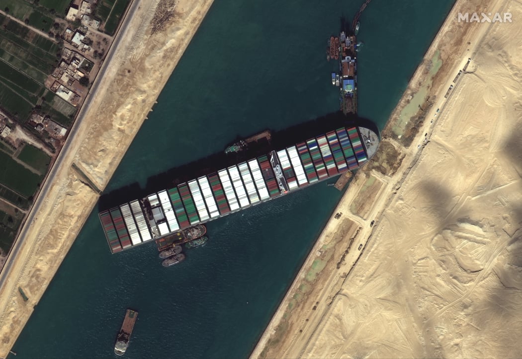 Tug boats and dredgers on March 27, 2021, attempting to free the ship Ever Given, which was lodged sideways and impeding all traffic across Egypt's Suez Canal.