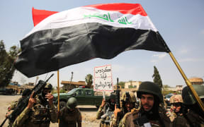 Members of the Iraqi federal police wave national flags during a military parade as they celebrate in the Old City of Mosul, where the gruelling battle to retake Iraq's second city from Islamic State (IS) group fighters is now nearing its end, on July 2, 2017.
