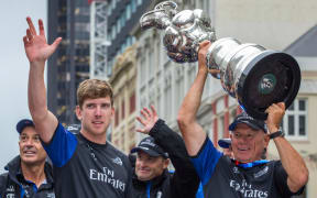 Team New Zealand helmsman Peter Burling and Team New Zealand Boss Grant Dalton hold aloft the Americas Cup during the Emirates Team New Zealand victory Parade held in Auckland in July 2017.